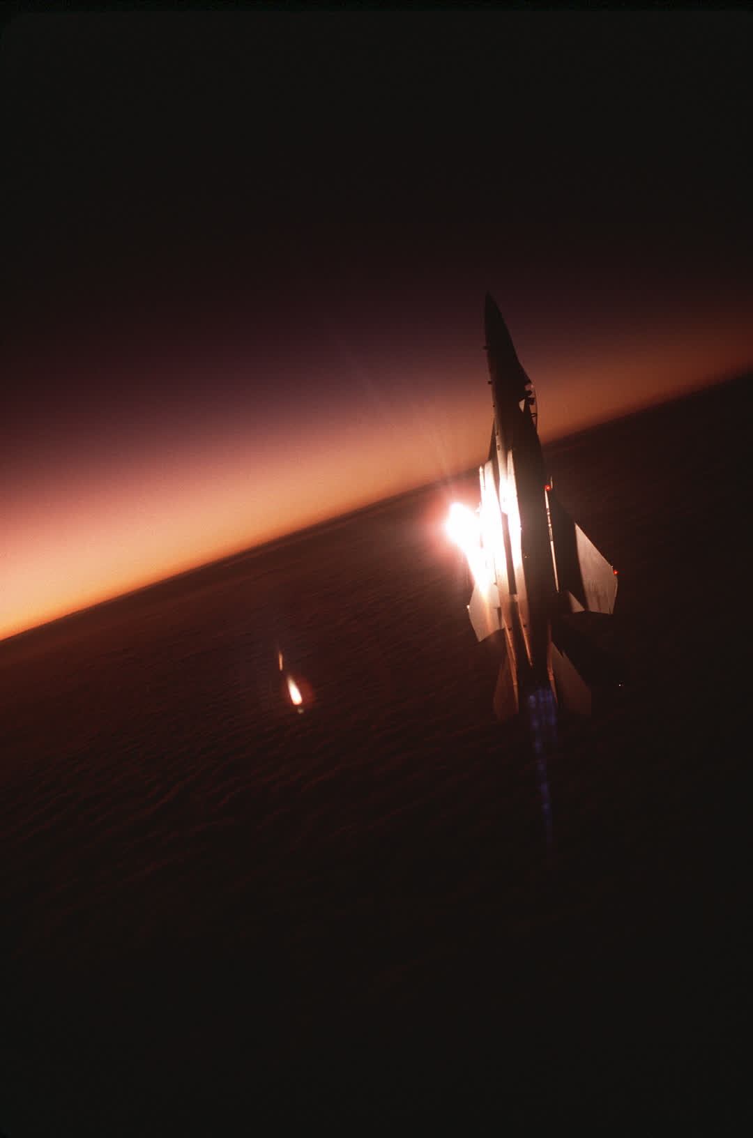 מטוס F-15 בנסיקה אנכית בשקיעה, מבער מלא דולק ונור נורה מזנבו